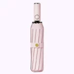 Parapluie anti retournement rose pliable avec rayures, solide et résistant au vent, design élégant pour une protection optimale.