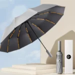 Parapluie anti-retournement gris et noir, rayures orange, avec étui élégant et boîte, design moderne, résistant au vent.