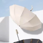 Parapluie anti-retournement crème, résistant au vent, structure noir et dorée, design élégant, idéal pour toutes saisons.