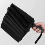Parapluie anti retournement pliable noir élégant, compact et pratique, parfait pour rester au sec avec style sous la pluie.