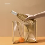 Parapluie automatique doré élégant rangé dans un sac transparent avec des oranges, accessoire chic de la collection [Collection].