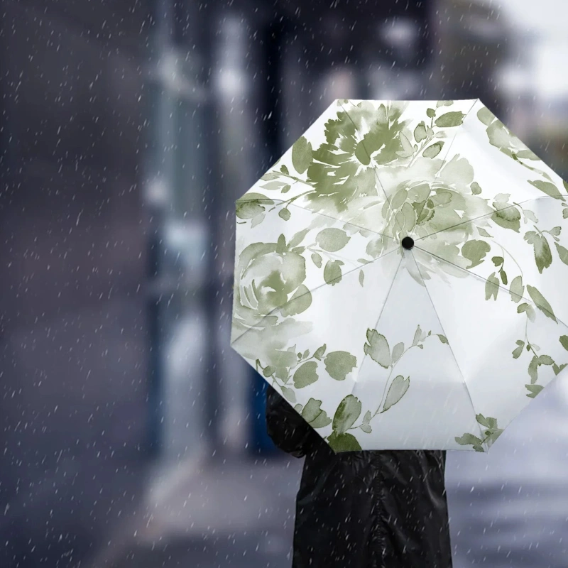 Parapluie automatique vert sauge avec motifs feuillage, élégant et pratique, idéal sous la pluie, arrière-plan flou.