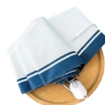Parapluie automatique blanc avec bord bleu marine, design élégant, plié sur une surface en bois, accessoire tendance.
