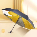 Parapluie noir design chat, intérieur dessins, collection moderne, accessoire élégant posé sur fond beige lumineux.