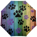 Parapluie manuel motifs empreintes de pattes, design coloré sur fond bois multicolore, accessoire pour amoureux des chiens et animaux.
