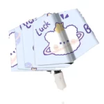 Parapluie enfant automatique ourson avec motifs ludiques de nuages et étoiles, teintes pastel et bleu, idéal pour la pluie.