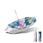 Parapluie droit noir beige anti-UV avec motif floral coloré, étui assorti et vaporisateur inclus pour une protection optimale.
