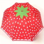 Parapluie manuel rouge motif fraise avec gouttes blanches et feuille verte, élégant et pratique pour rester au sec avec style.