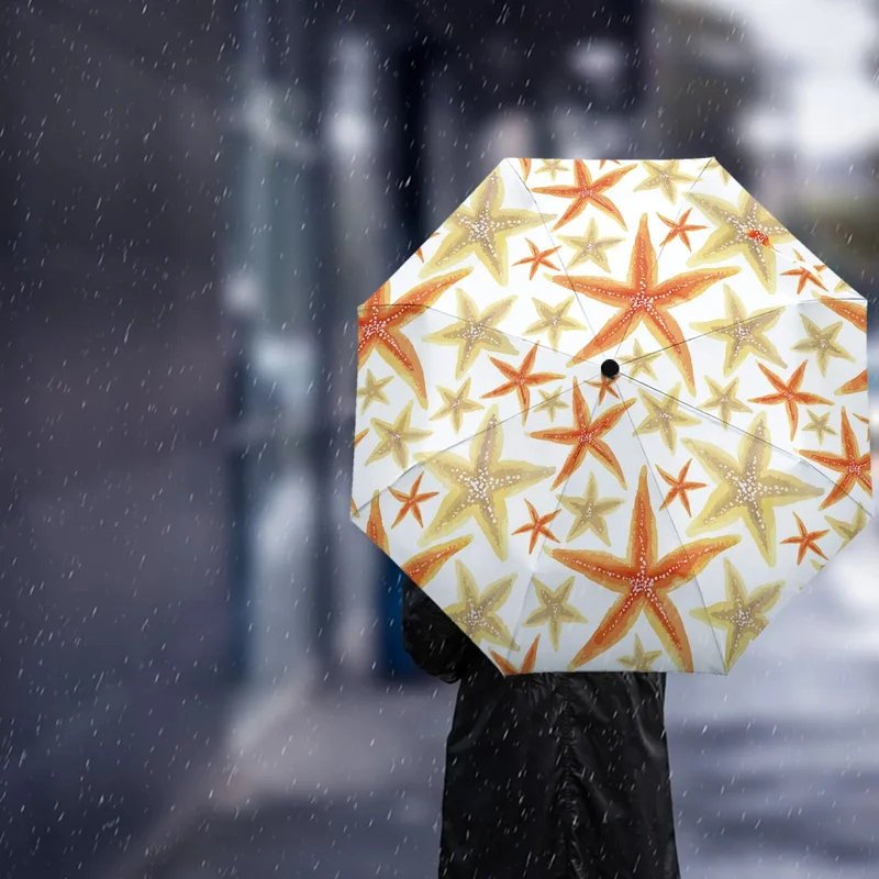 Parapluie orange automatique avec motifs étoiles de mer, octogonal, utilisé sous la pluie en ville avec un décor urbain flou en fond.