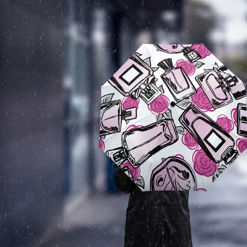 Parapluie rose automatique femme avec motifs élégants de flacons de parfum et roses, parfait pour rester chic sous la pluie.