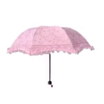 Parapluie pliant rose dentelle avec bord froufrou, chic et féminin, idéal pour allier protection contre la pluie et élégance.