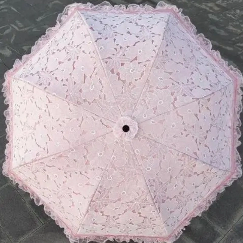 Parapluie pliant rose en dentelle élégante, motifs floraux et bord festonné, parfait pour mariages et occasions spéciales.