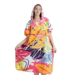 Femme en poncho de bain coloré à motifs abstraits, avec capuche, alliant confort et style pour rester tendance après la baignade.