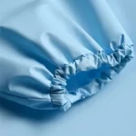 Poncho imperméable bleu clair pour bébé et enfant, motif [Collection], gros plan sur le tissu et le plissage unique du design.