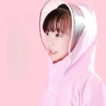 Poncho pluie imperméable rose pour bébé et enfant avec capuche, idéal pour temps pluvieux, design tendance devant un fond rose.