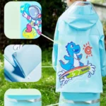 Poncho imperméable enfant motif dinosaure surfeur et astronaute, pratique pour la pluie avec détails boutons et bretelles.