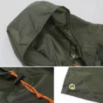 Poncho de pluie homme vert kaki avec capuche, cordon orange ajustable et finitions renforcées pour une protection optimale.
