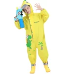 Enfant joyeux en poncho imperméable 3D dinosaure jaune, jouant sous la pluie avec un pistolet à eau, idéal pour moments ludiques.