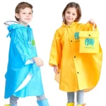 Deux enfants souriants en poncho imperméable, bleu et jaune, avec bottes de pluie, montrant un sac assorti. Poncho enfant oreille.