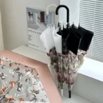 Parapluie canne transparent motif chat avec large bord, design élégant, présenté sur table avec éclairage naturel en arrière-plan.