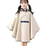 Petite fille souriante en poncho imperméable beige à capuche avec détails bleu marine, parfait pour les journées pluvieuses.