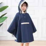 Petite fille souriante en poncho de pluie bleu marine avec capuche, idéale pour les jours pluvieux, devant un fond clair.