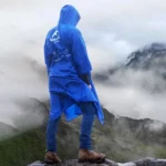 Homme portant un poncho pluie bleu de la collection [Collection], idéal pour protéger contre les intempéries en montagne.