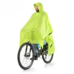 Homme en poncho de pluie vert fluorescent sur un vélo, protégé contre la pluie, accessoire pratique pour temps humide.