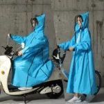 Femme en poncho imperméable bleu à capuche sur scooter/vélo, protection pluie unisexe, idéale pour homme et femme, fermeture éclair.