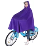 Femme sur un vélo bleu portant un poncho violet, alliant style et praticité contre la pluie pour les déplacements à vélo.