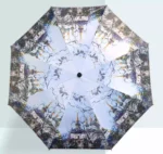 Parapluie rétro artistique avec motifs urbains stylisés, ouvert en vue aérienne, alliant élégance et fonctionnalité sous la pluie.