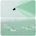 Parapluie compact vert avec gouttes d'eau sur tissu imperméable, parfait pour protection contre la pluie et facile à transporter.