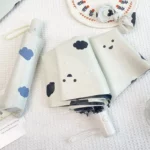 Echantillon de 2 beaux parapluies automatiques beiges avec nuages bleus et nuages noirs.