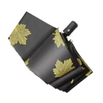Parapluie pliant noir au motif élégant de feuilles dorées, design compact et chic idéal pour une protection stylée contre la pluie.