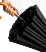 Parapluie noir élégant avec poignée bois courbée, 24 baleines, design raffiné et robuste, idéal pour rester chic sous la pluie.