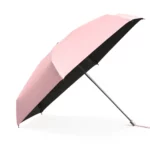 Parapluie rose clair avec doublure noire, compact et élégant.