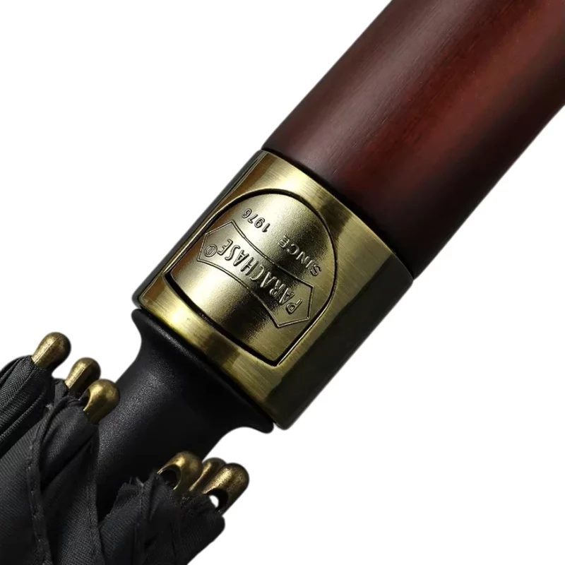 Pommeau de luxe en bois sombre avec anneau doré gravé, symbole de qualité et de tradition artisanale pour un très bon parapluie de golf.