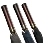 Pommeaux de parapluie en bois sombre et bagues dorées, symbole de qualité et d’artisanat pour un parapluie de golf d’exception.