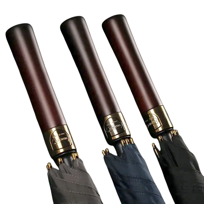 Pommeaux de parapluie en bois sombre et bagues dorées, symbole de qualité et d’artisanat pour un parapluie de golf d’exception.