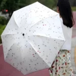 Parapluie blanc à motif floral discret. Léger et pratique, protège du soleil et de la pluie. Un accessoire chic pour femme.