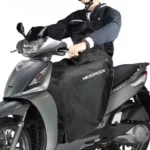 Tablier scooter coupe-vent en utilisation réelle. Protège efficacement du froid, du vent et de la pluie pour des trajets confortables.