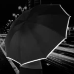 Parapluie noir avec bande réfléchissante, idéal de nuit en ville. Grande envergure, sécurité et visibilité accrues. Style sobre, efficace.
