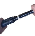 Zoom sur le mécanisme d'ouverture du parapluie noir. Manche robuste, système sécurisé, fabrication haut de gamme.