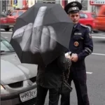 Parapluie noir doigt d'honneur utilisé en rue. Impact visuel garanti. Un design qui ne passe pas inaperçu.