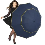 Femme élégante sous la pluie avec parapluie XXL bleu marine et bordures jaunes, alliant style et grande résistance.