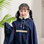 Poncho de pluie bleu marine pour enfant, avec poche frontale et capuche doublée. Protection efficace et design élégant pour les journées pluvieuses.