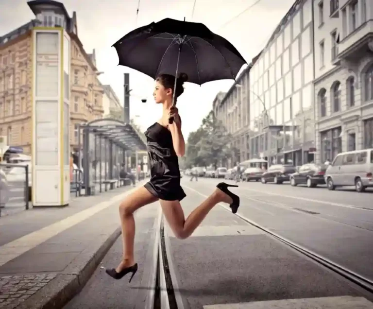 Scène urbaine dynamique : femme chic courant sous la pluie avec un parapluie noir. Élégance et urgence.