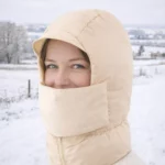 Capuche beige isolante avec cache-visage. Protection complète contre le froid, vent et neige. Style outdoor, idéale ski, rando et sorties hivernales.