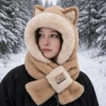 Femme portant une cagoule douce avec oreilles de chat dans une forêt enneigée, accessoire chaud et tendance pour l’hiver.