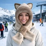Femme souriante avec cagoule à oreilles de chat beige sur une station de ski, look cosy et stylé pour affronter le froid.